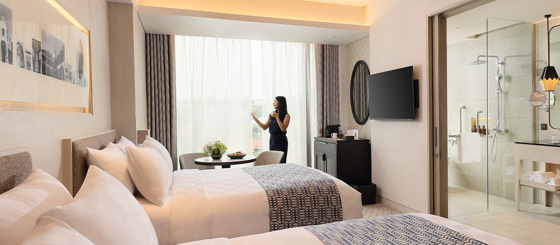 A woman looking at the panoramic view of Semarang from the spacious premier room at Padma Hotel Semarang